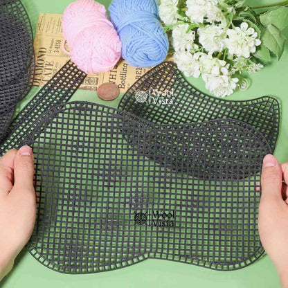 Hands holding black plastic mesh sheet pieces for a saddle bag with pink and blue yarn