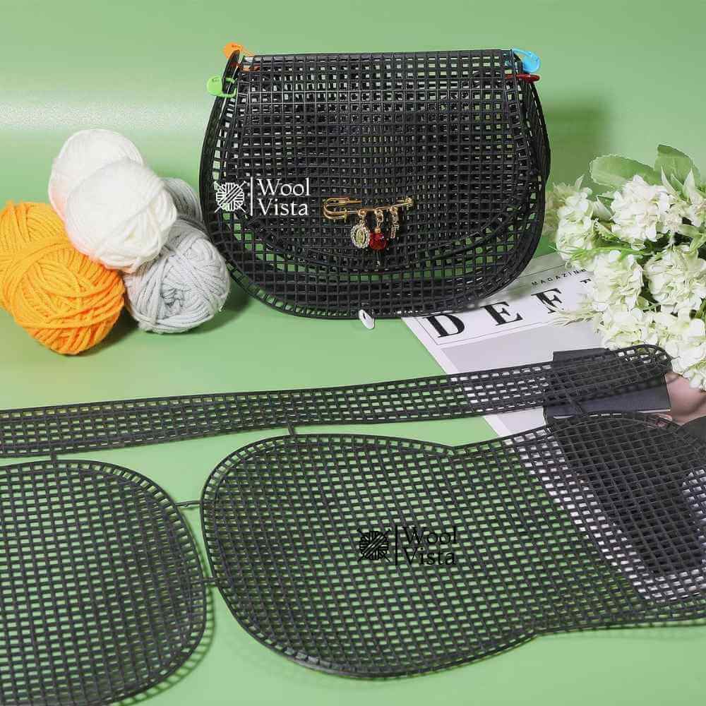 Black plastic mesh sheet pieces and finished black crossbody saddle bag with charm pin and yarn balls